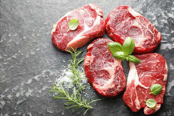 Koyu masa üzerinde çiğ et ve baharat parçaları, düz. Metin için boşluk