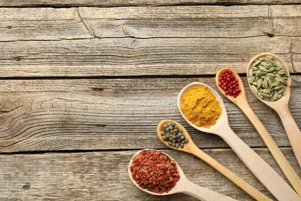 Tahta masadaki kaşıklardaki farklı aromatik baharatlar. Metin için boşluk