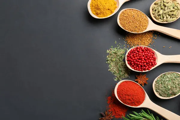 Siyah masadaki kaşıklardaki farklı aromatik baharatlar. Metin için boşluk