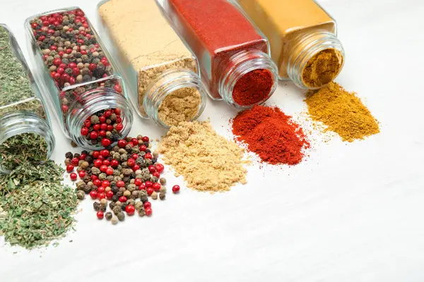 Beyaz masadaki kavanozlarda farklı aromatik baharatlar