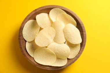 Sarı arka planda kasede patates cipsi, üst manzara.