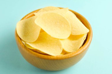 Açık mavi arka planda, kasede patates cipsi, yakın plan.