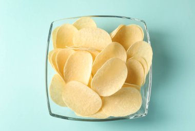 Açık mavi arka planda leziz patates cipsi, üst manzara.