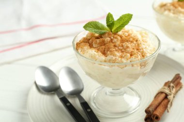 Tarçınlı lezzetli sütlaç ve beyaz masada nane, yakın plan.