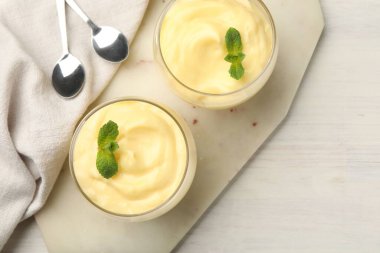 Beyaz ahşap masada servis edilen nane aromalı vanilyalı puding.
