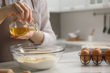 Khinkali yapıyorum. Kadın mutfaktaki masada kaseye yağ koyuyor, yakın plan.