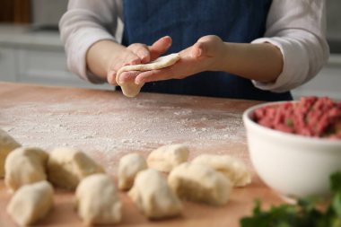 Khinkali yapıyorum. Mutfaktaki masada hamur şekillendiren kadın, yakın plan.