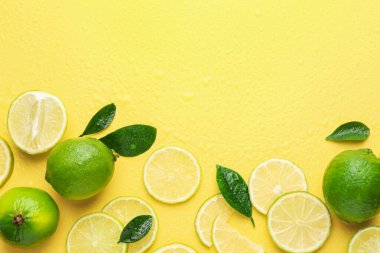 Taze limon ve yeşil yapraklar sarı arka planda, düz yerde. Metin için boşluk