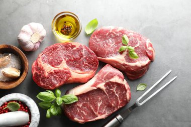 Çiğ et, baharat ve çatal parçaları gri masada, düz yatıyordu.