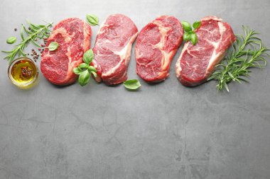 Çiğ et ve baharat parçaları gri masada, düz yerde. Metin için boşluk