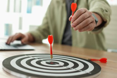 Dart tahtası olan bir adam, dizüstü bilgisayarda çalışırken, yakın plan.