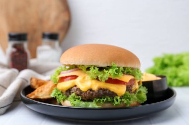 Sos ve patates dilimli leziz bir çizburger, yakın plan.