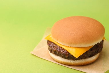 Yeşil arka planda lezzetli köfteli çizburger, yakın plan. Metin için boşluk