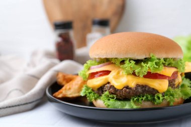 Sos ve patates dilimli leziz bir çizburger, yakın plan.