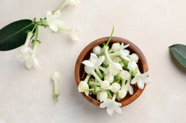 Üzerinde yasemin çiçekleri olan bir kase bej masa, düz uzanmış