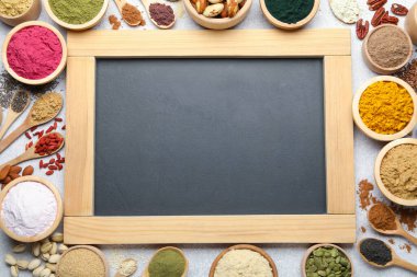 Farklı süper yiyecek tozları ve açık gri masa üzerinde karatahta, düz yatak. Metin için boşluk