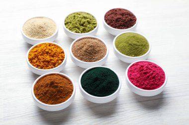 Beyaz ahşap masadaki farklı süper yiyecek tozları, yakın plan.