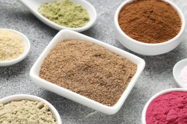 Gri desenli masada farklı süper yiyecek tozları, yakın plan.