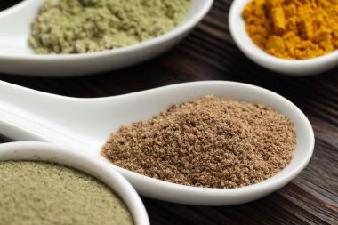 Tahta masadaki kaşıklarda farklı süper yiyecek tozları, yakın plan.