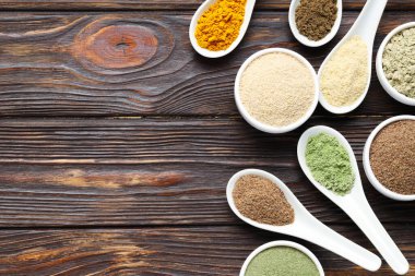 Tahta masada, düz yerde, kaşıklarda ve kaselerde farklı süper yiyecek tozları var. Metin için boşluk