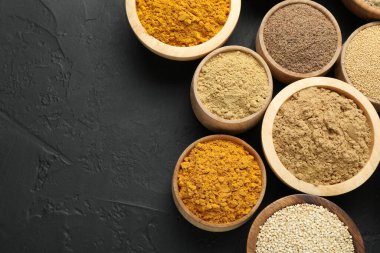 Koyu dokulu masada, düz yerde, kaselerde farklı süper yiyecek tozları var. Metin için boşluk