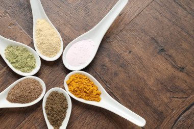 Tahta masadaki kaşıklardaki farklı süper yiyecek tozları. Metin için boşluk