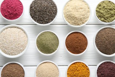 Beyaz ahşap masadaki kaselerdeki farklı süper yiyecek tozları.