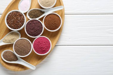 Kâselerdeki farklı süper yiyecekler ve beyaz ahşap masada kaşıklar, üst manzara. Metin için boşluk