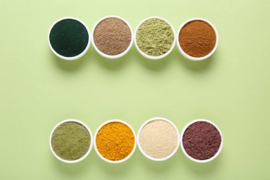 Açık yeşil arka planda, kaselerde farklı süper yiyecek tozları var. Metin için boşluk