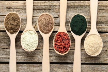 Tahta masadaki kaşıklardaki farklı süper yiyecekler.