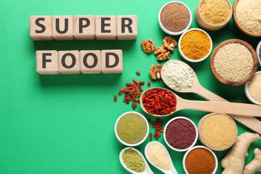 Farklı süper gıda ürünleri ve yeşil arka planda tahta küplerden yapılmış kelimeler.