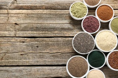 Tahta masadaki kaselerdeki farklı süper yiyecekler, düz yatış. Metin için boşluk