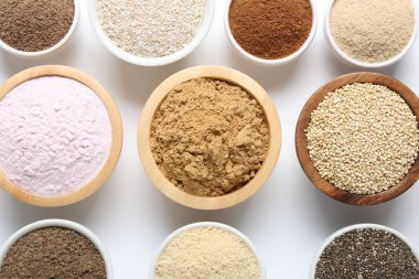 Beyaz arka planda kaselerde farklı süper yiyecek tozları var.