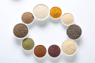 Beyaz arka plandaki kaselerde farklı süper yiyecek tozlarının çerçevesi düz. Metin için boşluk