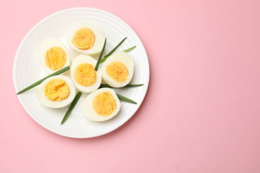 Pembe arka planda haşlanmış yumurta ve yeşil soğan. Metin için boşluk