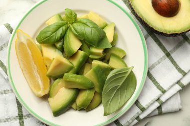 Lezzetli yeşil avokadolar, fesleğen ve limon masada, düz yerde.