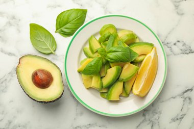 Lezzetli yeşil avokadolar, fesleğen ve limon beyaz mermer masa, düz yatıyordu.