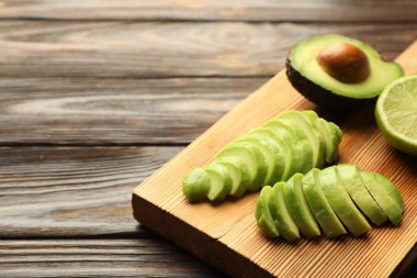 Olgun yeşil avokado ve limonu ahşap masada kes, yakın plan.