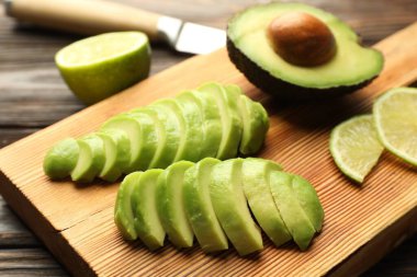 Olgun yeşil avokado ve limonu ahşap masada kes, yakın plan.