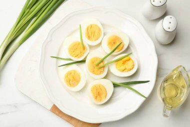 Haşlanmış yumurta ve beyaz masada yeşil soğan, düz.