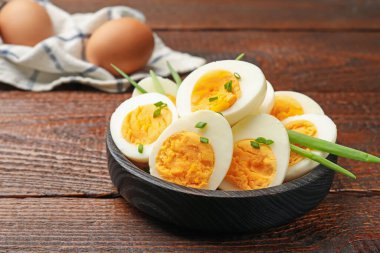 Haşlanmış yumurta ve ahşap masada yeşil soğan, yakın plan.