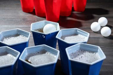 İçkili plastik bardaklar ve toplar ahşap masada, yakın plan. Bira pong oyunu