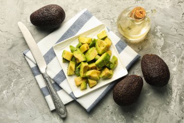 Gri desenli masa, düz uzanmış, sargı bezi ve bıçaklı leziz avokadolar.