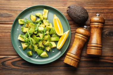 Lezzetli avokado roka, limon ve ahşap masa üzerinde sos, düz yatıyordu.