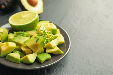 Lezzetli avokadolar, kekik ve limon siyah masada, yakın plan. Metin için boşluk