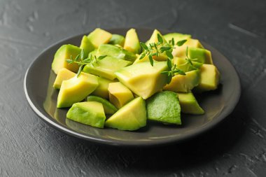 Lezzetli avokado ve kekik siyah masada, yakın plan.