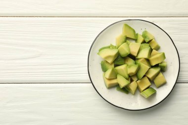 Beyaz ahşap masa üzerinde leziz kesilmiş avokadolar, üst manzara. Metin için boşluk