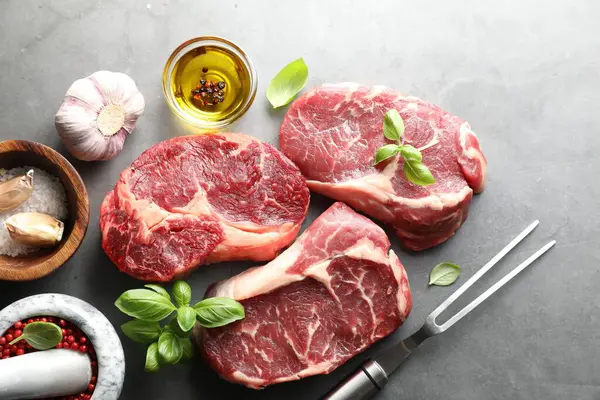 Çiğ et, baharat ve çatal parçaları gri masada, düz yatıyordu.