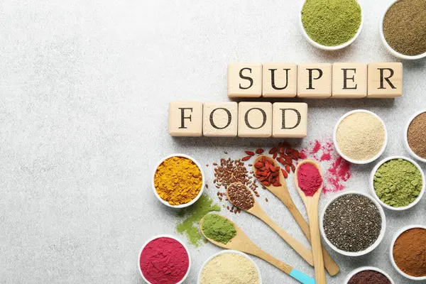 Farklı süper yiyecek tozları ve açık gri masadaki küplerden yapılmış düz yataklar. Metin için boşluk