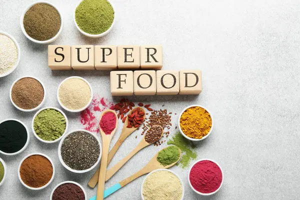 Farklı süper yiyecek tozları ve açık gri masadaki küplerden yapılmış düz yataklar. Metin için boşluk